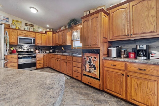 6203 County Road 1750, West Plains, MO 65775 - kitchen with appliances with stainless steel finishes, a sink, tasteful backsplash, brown cabinets, and vaulted ceiling