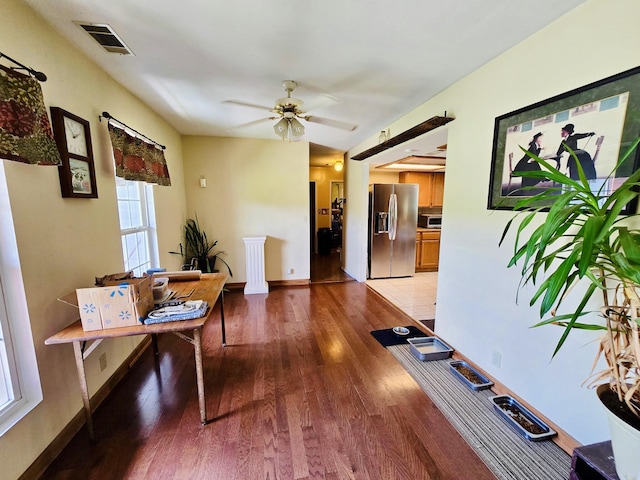 office space with light wood-style flooring, a ceiling fan, and baseboards