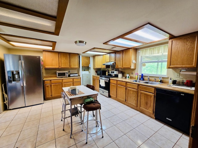 kitchen with black appliances, a sink, under cabinet range hood, and light tile patterned flooring