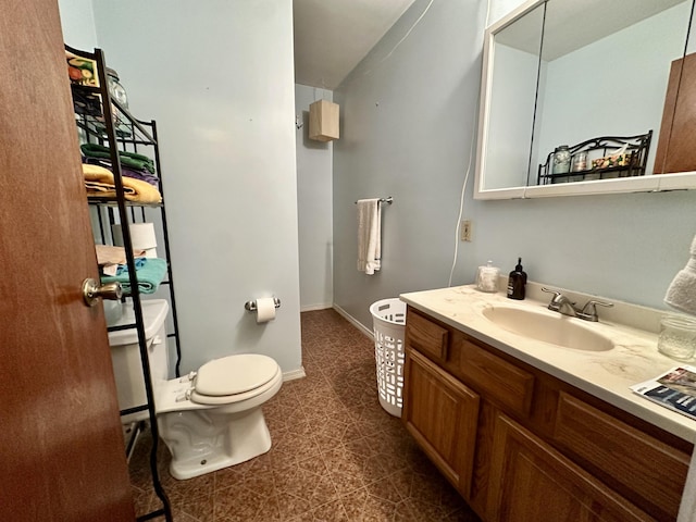 bathroom with vanity, toilet, and baseboards