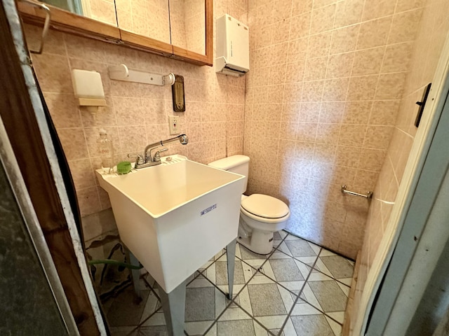 bathroom featuring pet washing station, toilet, tile walls, and a sink