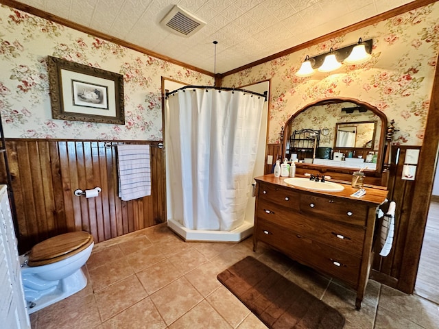 full bath with crown molding, a stall shower, wainscoting, vanity, and toilet