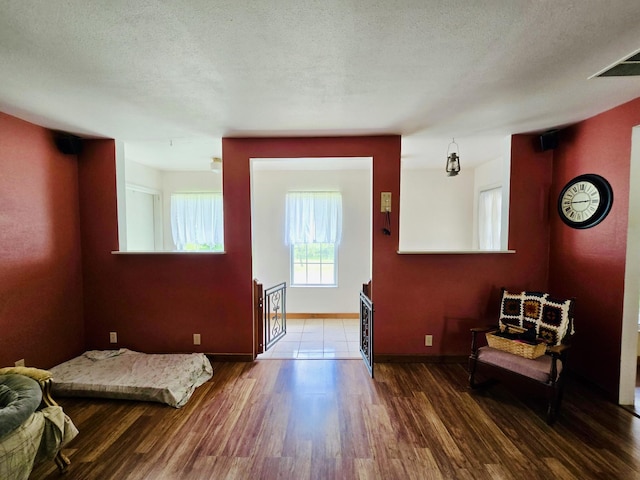 foyer entrance with wood finished floors, baseboards, and a textured ceiling