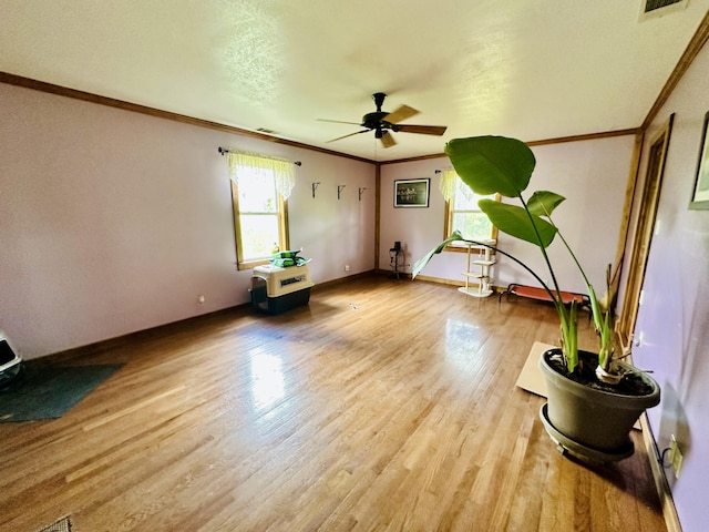 unfurnished room with ceiling fan, crown molding, light wood finished floors, and baseboards