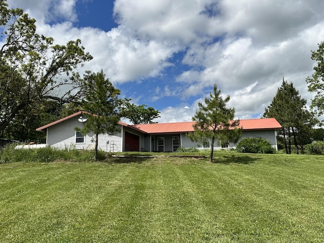 back of house featuring an attached garage, a lawn, and metal roof