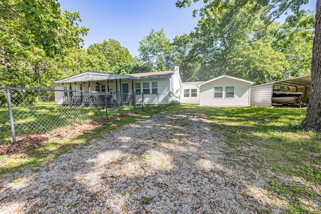 back of house with a chimney, driveway, covered porch, and a carport