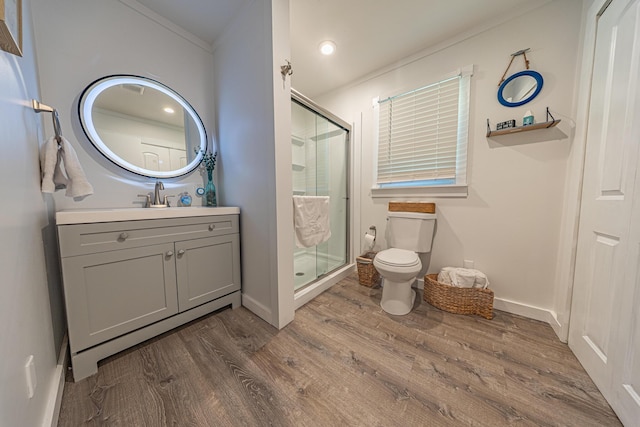 bathroom featuring toilet, ornamental molding, a shower stall, wood finished floors, and vanity