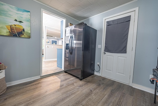 interior space with stainless steel fridge, ornamental molding, wood finished floors, and baseboards