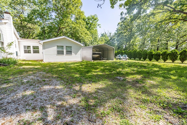 view of green lawn with a carport and view of wooded area