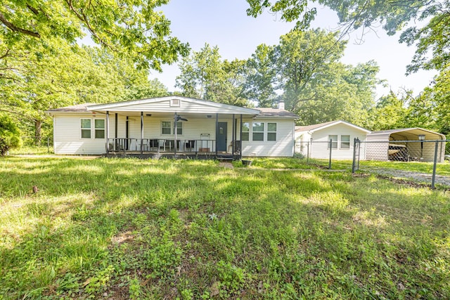 rear view of property featuring a detached carport, a porch, fence, and a chimney