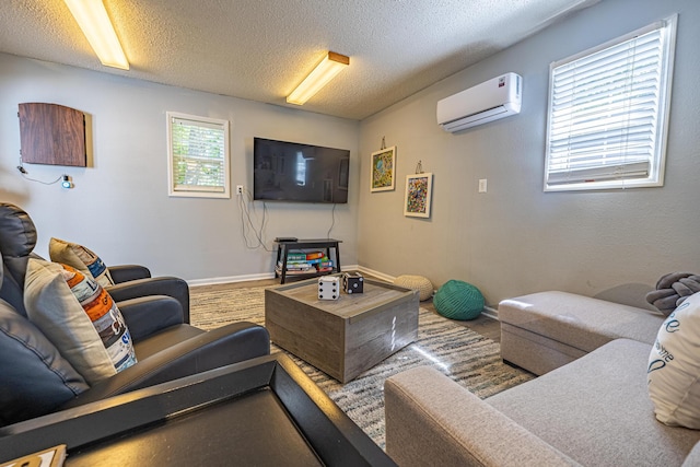 living room featuring a wall mounted AC, a textured ceiling, and baseboards