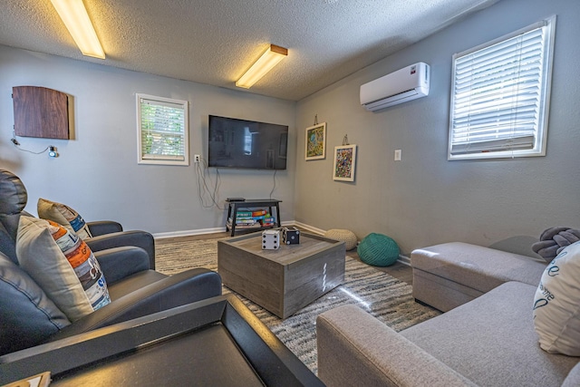 living room featuring a wall unit AC, baseboards, and a textured ceiling
