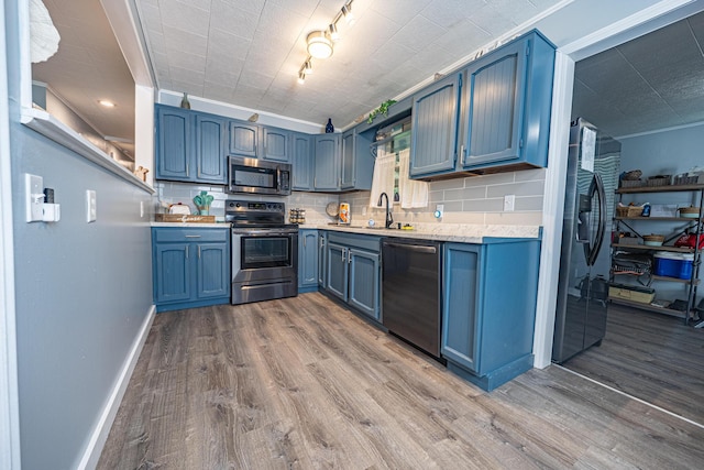 kitchen featuring stainless steel appliances, blue cabinets, a sink, and light countertops