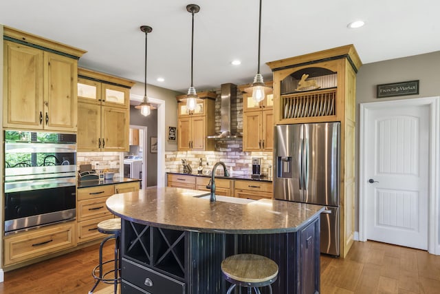 103 Dogwood Ct, Saddlebrooke, MO 65630 - kitchen featuring wall chimney range hood, stainless steel appliances, a sink, a breakfast bar, and a kitchen island with sink