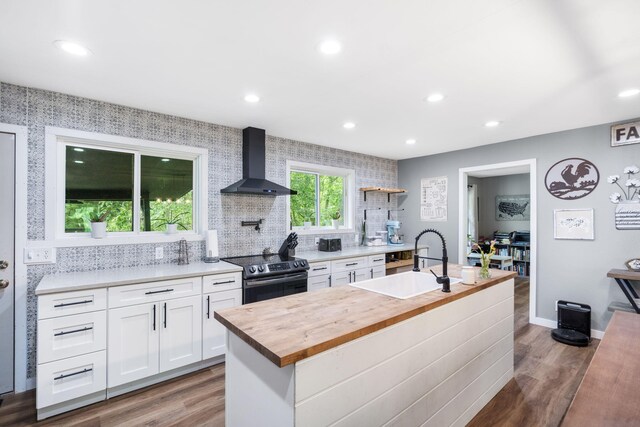 3662 N Farm Rd Unit 127, Springfield, MO 65803 - kitchen with wall chimney exhaust hood, stainless steel electric range oven, butcher block countertops, a sink, and wood finished floors