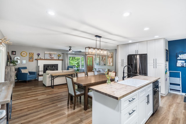 3662 N Farm Rd Unit 127, Springfield, MO 65803 - kitchen with a sink, stainless steel fridge, a brick fireplace, light wood-style floors, and white cabinetry