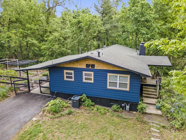 3662 N Farm Rd Unit 127, Springfield, MO 65803 - view of side of property with a chimney, central air condition unit, driveway, a wooden deck, and roof with shingles