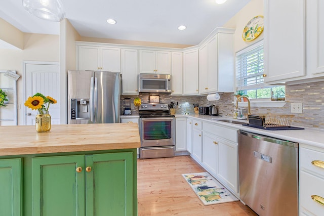 kitchen featuring stainless steel appliances, butcher block countertops, a sink, white cabinets, and decorative backsplash