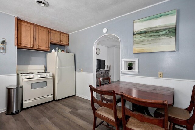 2708 N Fremont Ave, Springfield, MO 65803 - kitchen with white appliances, brown cabinets, a wainscoted wall, arched walkways, and dark wood-style flooring