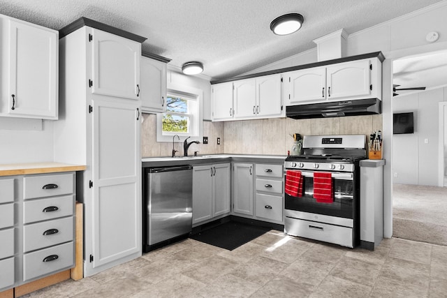 kitchen featuring gas range, under cabinet range hood, white cabinets, a sink, and a textured ceiling