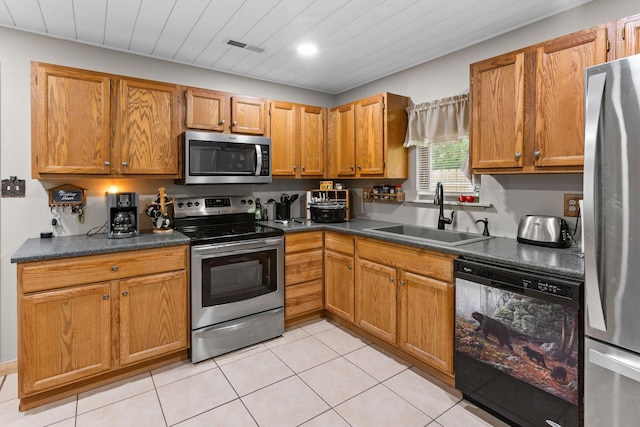 229 Grand Slam Ave, Cape Fair, MO 65624 - kitchen featuring stainless steel appliances, a sink, dark countertops, light tile patterned floors, and brown cabinets