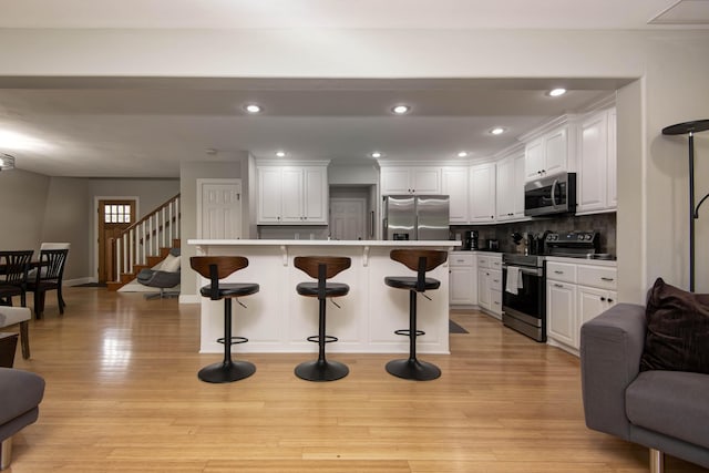 700 E Delmar St, Springfield, MO 65807 - kitchen with stainless steel appliances, a breakfast bar, white cabinets, backsplash, and recessed lighting