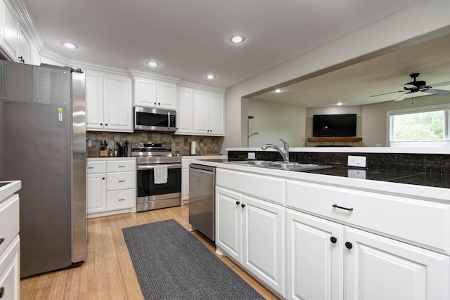 700 E Delmar St, Springfield, MO 65807 - kitchen featuring stainless steel appliances, a sink, white cabinets, decorative backsplash, and light wood-style floors