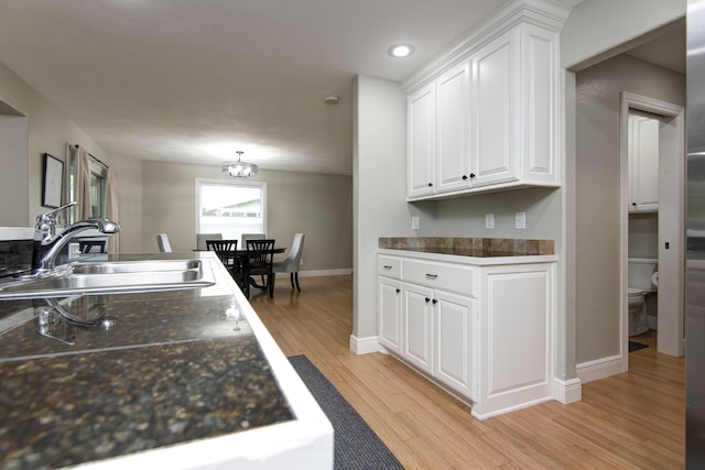 700 E Delmar St, Springfield, MO 65807 - kitchen with a sink, white cabinetry, light wood-style floors, baseboards, and dark countertops