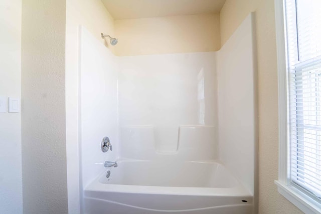 full bath featuring shower / bathtub combination and a textured wall