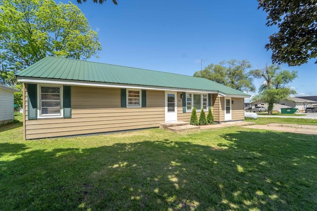 ranch-style house featuring a front lawn and metal roof