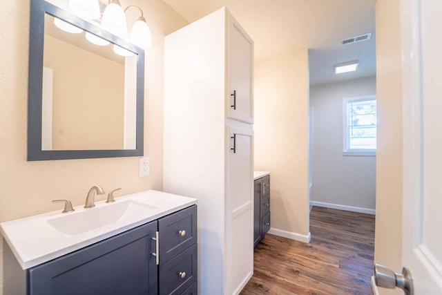 bathroom with vanity, wood finished floors, and baseboards
