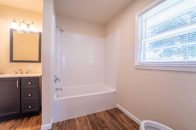 full bathroom with wood finished floors, baseboards, washtub / shower combination, and vanity