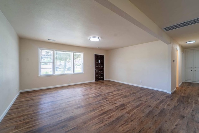spare room featuring dark wood finished floors and baseboards