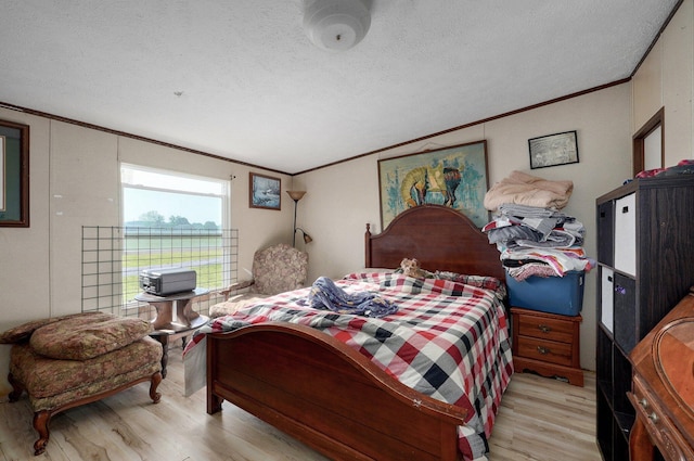bedroom with crown molding, light wood-style floors, and a textured ceiling