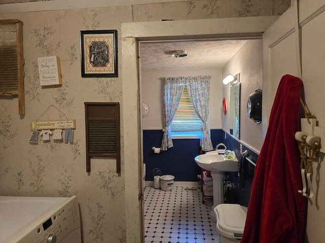 3590 County Road 7140, West Plains, MO 65775 - bathroom with washer / clothes dryer, a textured ceiling, wainscoting, and a sink