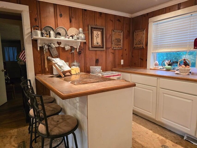 3590 County Road 7140, West Plains, MO 65775 - kitchen featuring tile countertops, a kitchen bar, white cabinets, crown molding, and a peninsula