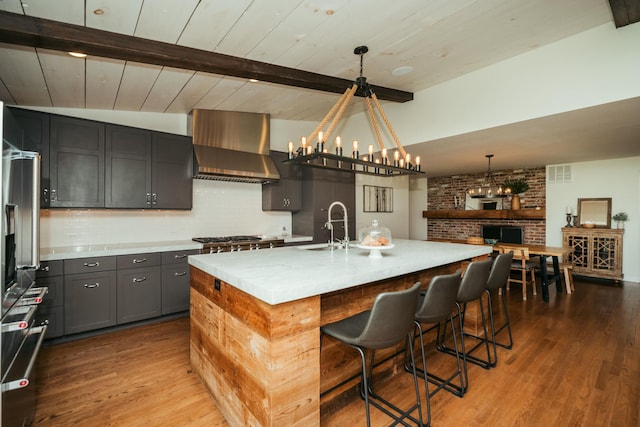 5724 E Mill St, Springfield, MO 65802 - kitchen with a sink, wood finished floors, wall chimney exhaust hood, backsplash, and a chandelier