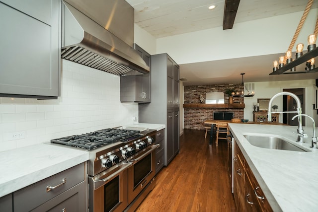 5724 E Mill St, Springfield, MO 65802 - kitchen with range with two ovens, wall chimney exhaust hood, a sink, dark wood-style flooring, and brick wall