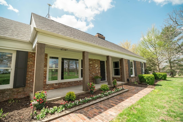 5724 E Mill St, Springfield, MO 65802 - view of side of home featuring a porch, brick siding, a chimney, roof with shingles, and a lawn