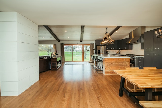 5724 E Mill St, Springfield, MO 65802 - kitchen featuring wall chimney exhaust hood, appliances with stainless steel finishes, light countertops, beamed ceiling, and light wood finished floors