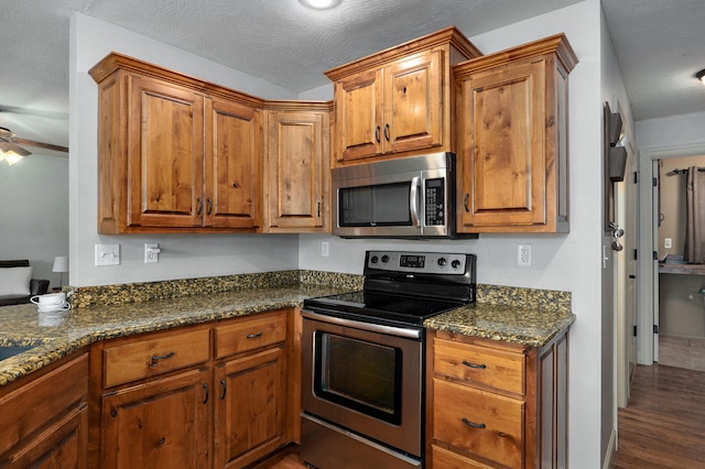 1428 S Appomattox Ave, Republic, MO 65738 - kitchen featuring appliances with stainless steel finishes, brown cabinets, wood finished floors, ceiling fan, and dark stone counters