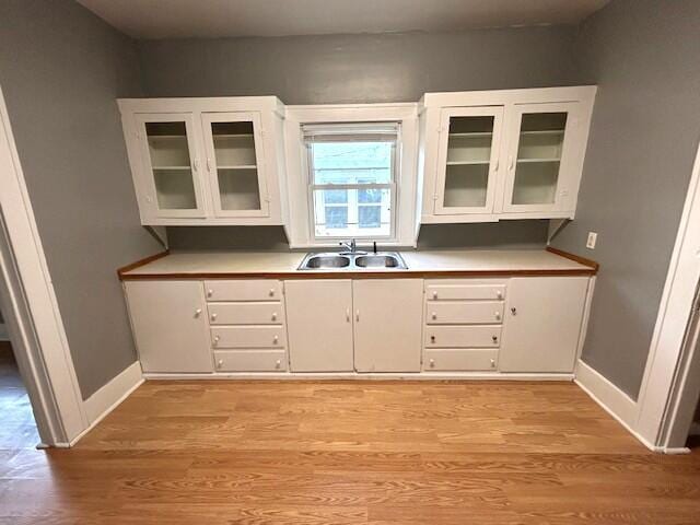 2238 N Rogers Ave, Springfield, MO 65803 - kitchen featuring a sink, light wood-type flooring, and white cabinetry
