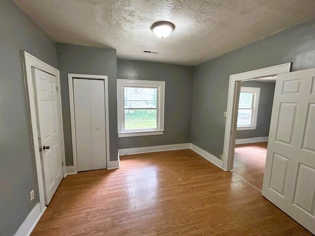 2238 N Rogers Ave, Springfield, MO 65803 - unfurnished bedroom featuring wood finished floors, a textured ceiling, and baseboards
