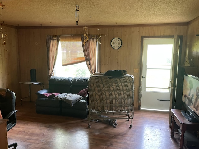 sitting room featuring wood walls, plenty of natural light, a textured ceiling, and wood-type flooring