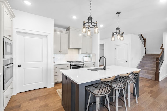 4531 E Hidden Oak St, Springfield, MO 65802 - kitchen featuring a sink, appliances with stainless steel finishes, a kitchen bar, light wood finished floors, and tasteful backsplash