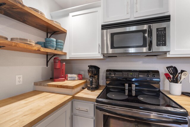 17 Montague Ln, Kimberling City, MO 65686 - kitchen with stainless steel microwave, butcher block countertops, electric range, open shelves, and white cabinetry