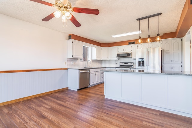 150 Sunken Forest Dr Unit 190, Forsyth, MO 65653 - kitchen with stainless steel appliances, a textured ceiling, white cabinets, dark wood-type flooring, and decorative backsplash