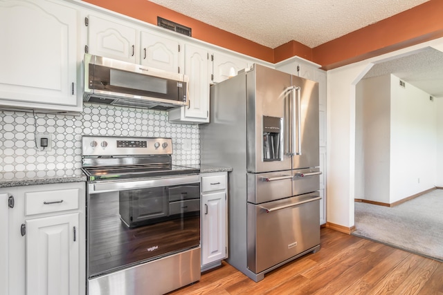 150 Sunken Forest Dr Unit 190, Forsyth, MO 65653 - kitchen featuring appliances with stainless steel finishes, a textured ceiling, white cabinets, light wood-style flooring, and tasteful backsplash