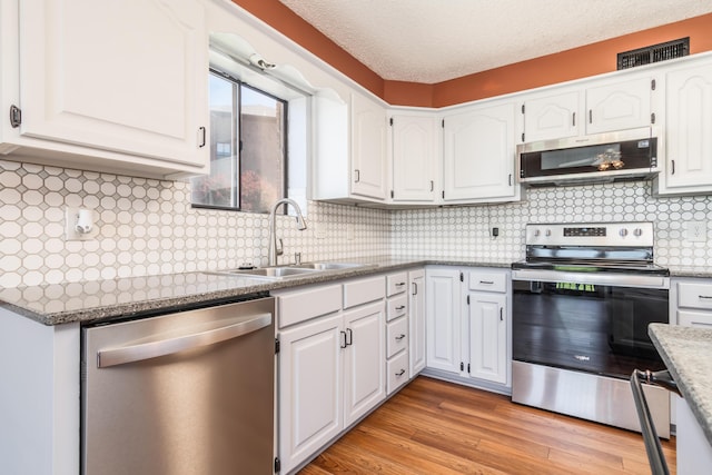 150 Sunken Forest Dr Unit 190, Forsyth, MO 65653 - kitchen featuring stainless steel appliances, a sink, white cabinets, light wood finished floors, and backsplash