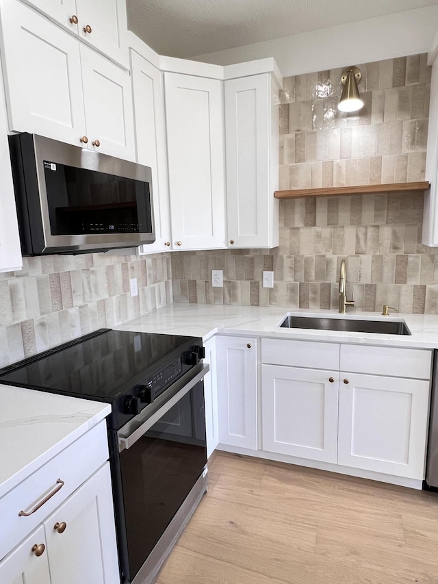 2077 N Sun Valley Dr, Springfield, MO 65802 - kitchen with stainless steel microwave, black electric range oven, a sink, open shelves, and white cabinetry